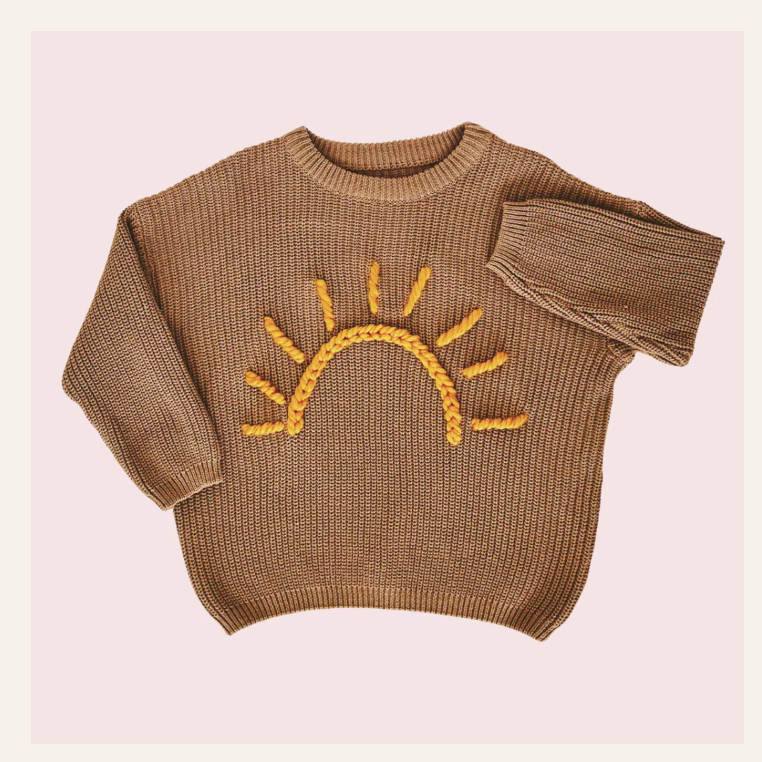 Brown sweater with a yellow sun design on a pink background