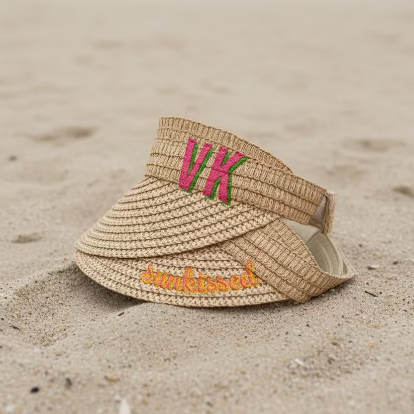 Beige visor with embroidered text on a white surface