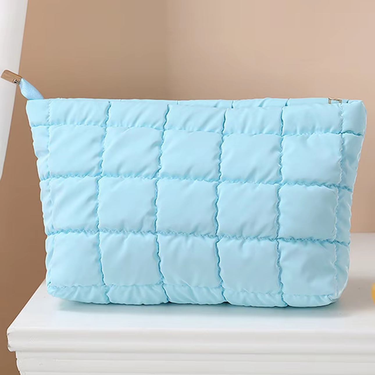 Light blue quilted pouch on a beige background