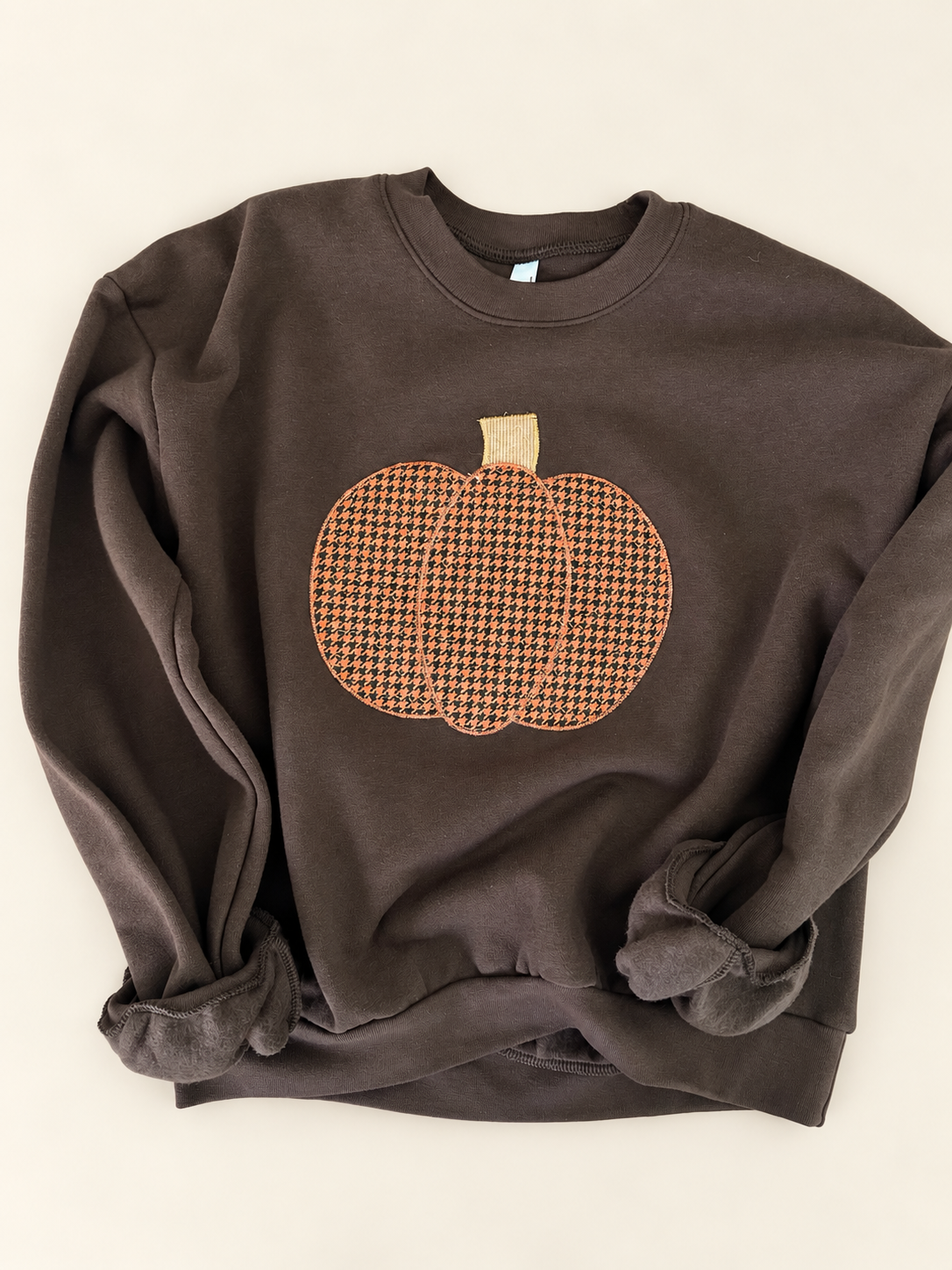Chocolate-brown crewneck sweatshirt with an orange houndstooth pumpkin design