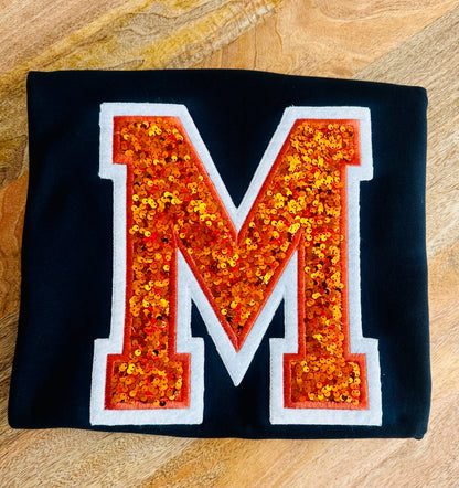 Black fabric with a large orange sequin letter &