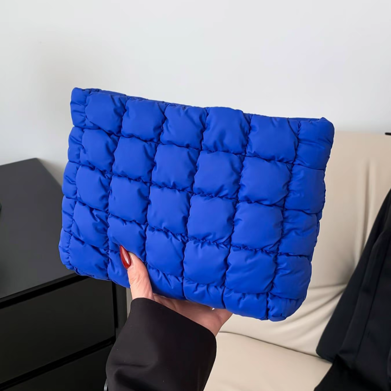 Blue puffer pillow held by a person against a neutral background