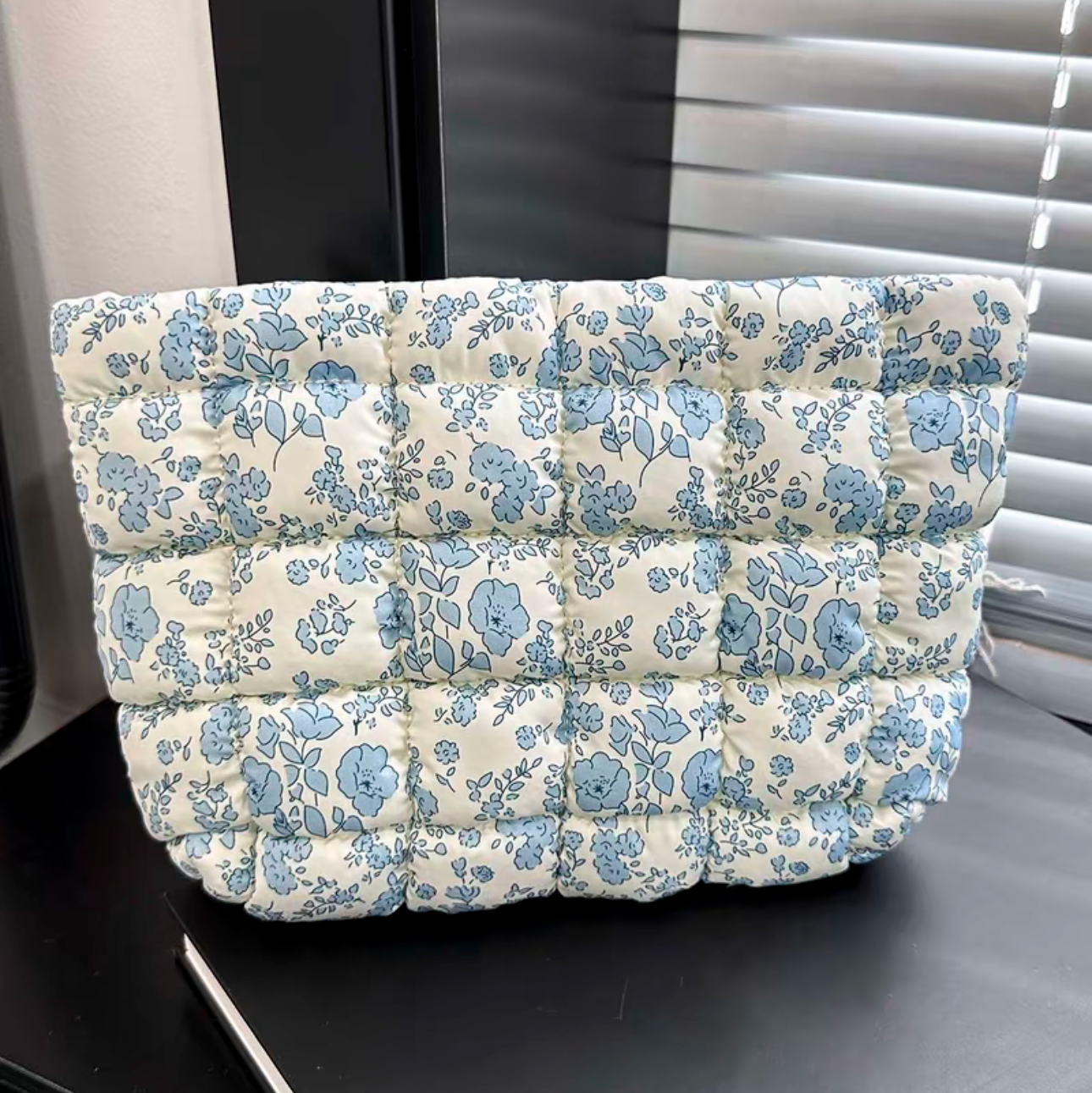 Floral-patterned cushion on a black surface with a window in the background
