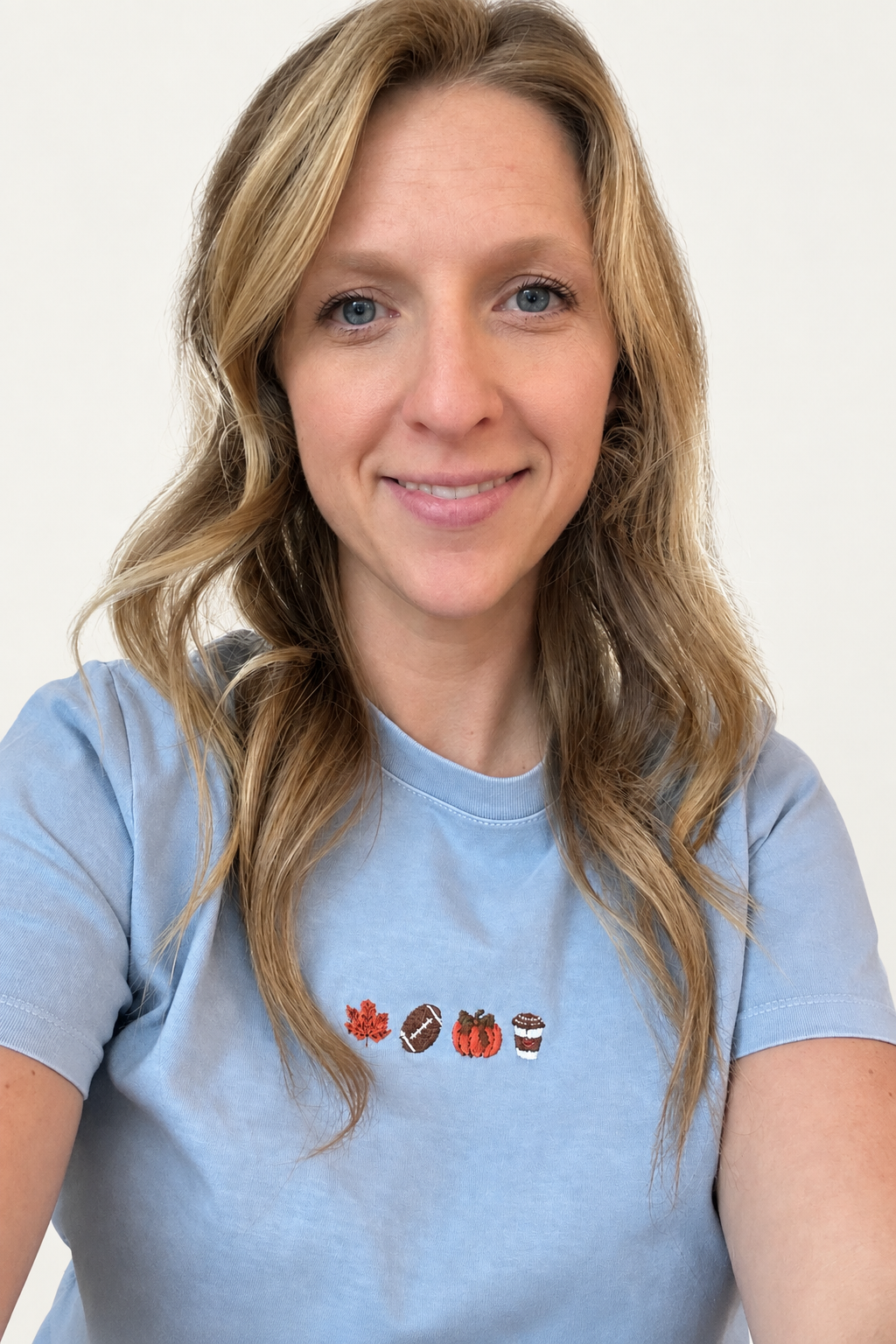 Model wearing a light-blue T-shirt with four small fall-themed embroidered motifs